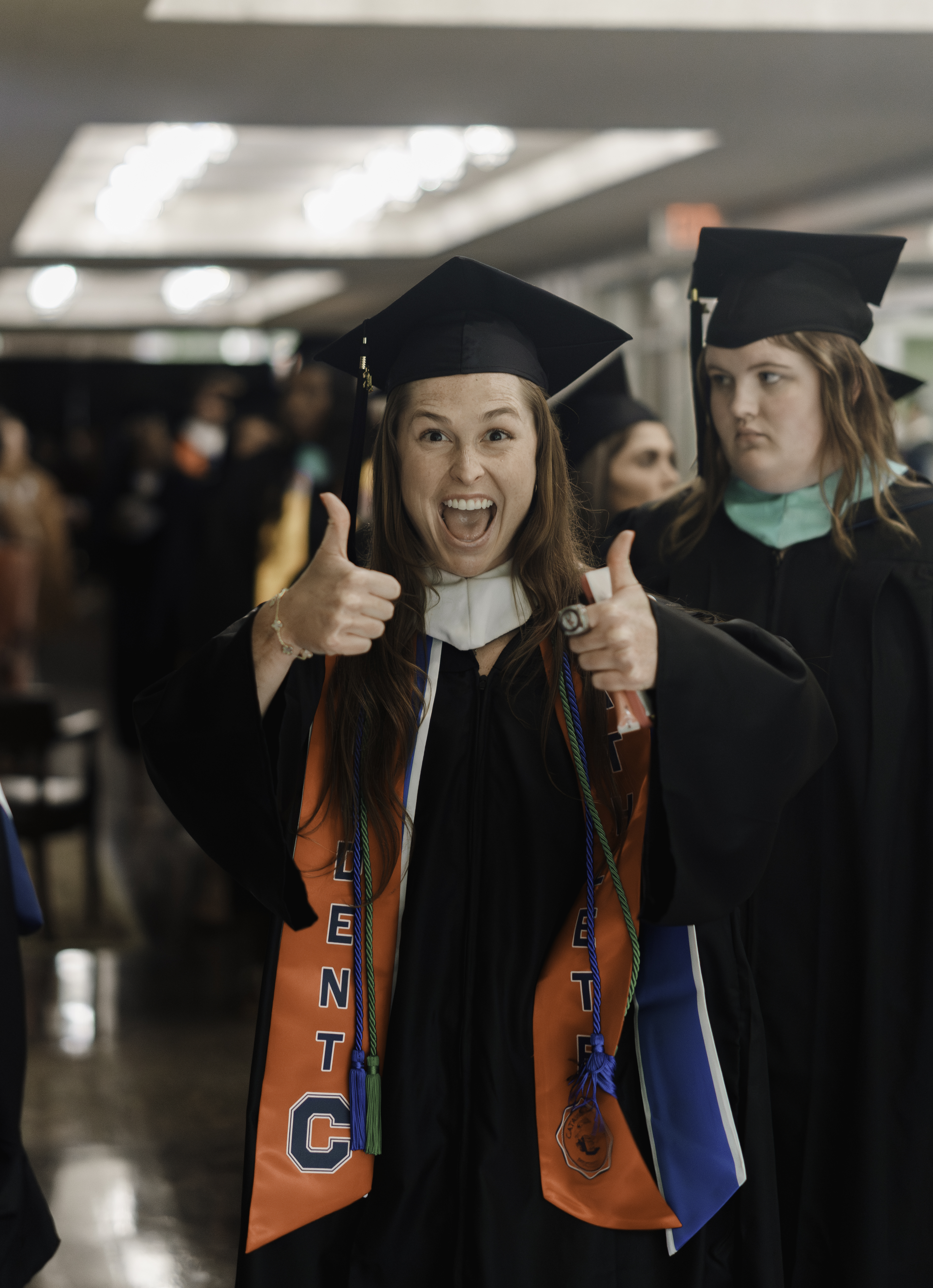 Female student-athlete graduate giving a double thumbs up