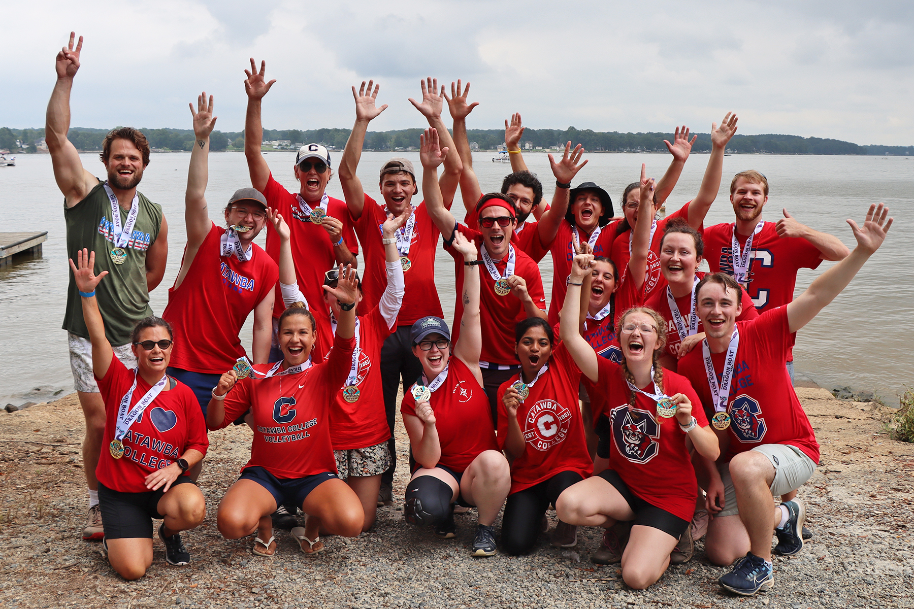 Catawba's Dragonboat team poses with their gold medals and hands up