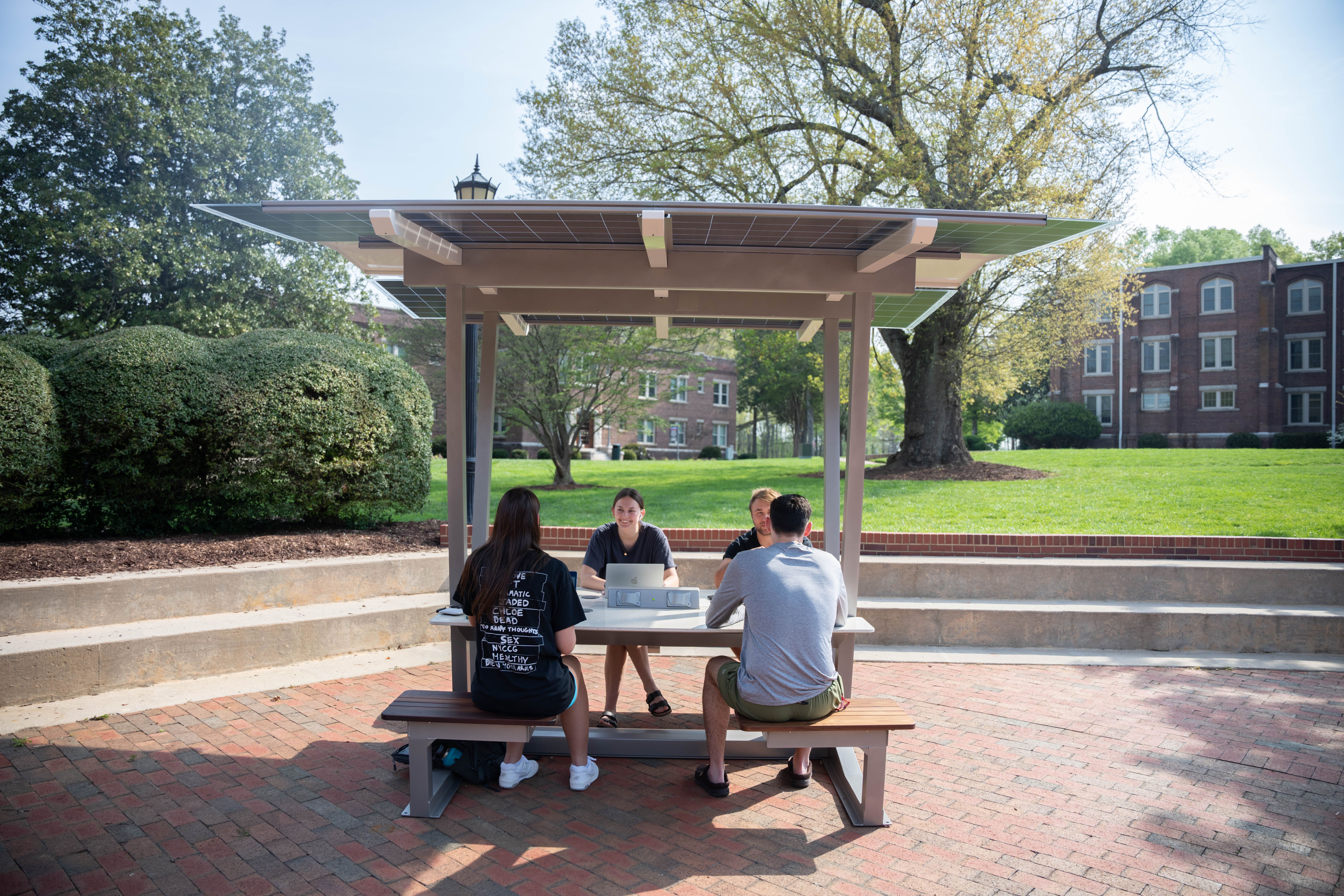 Haven solar shelter with students sitting at it on Stanback Plaza