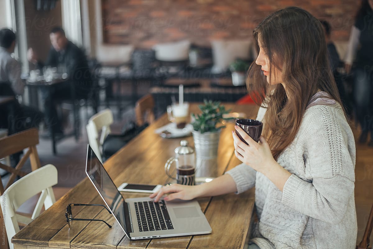 Online Student working at laptop in coffee shop