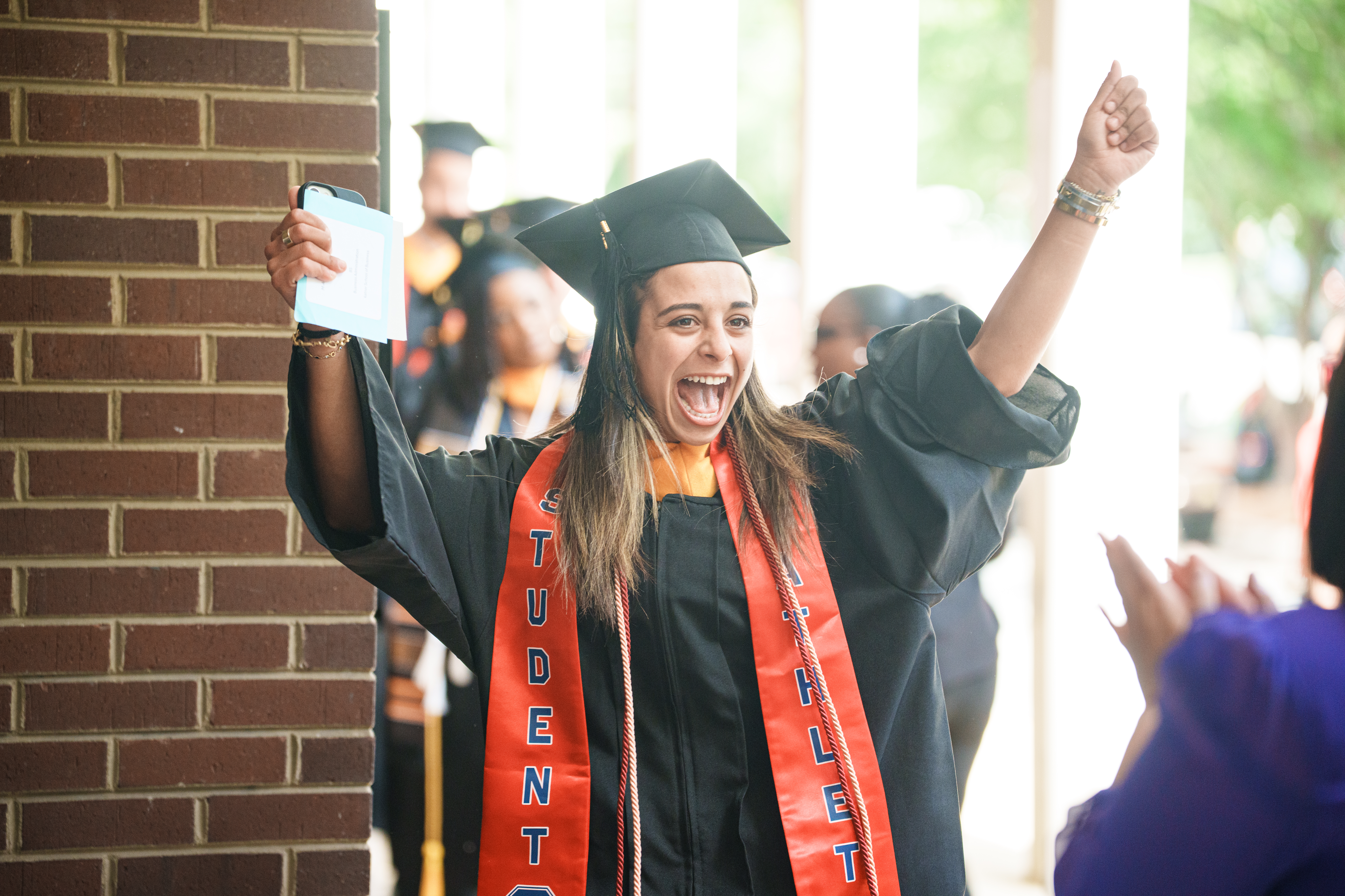 Female Catawba College graduate smiling and excited in her regalia