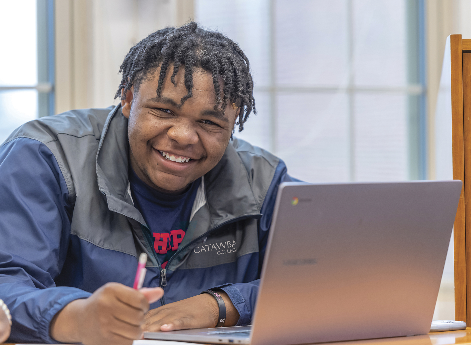 Student in class with laptop smiling
