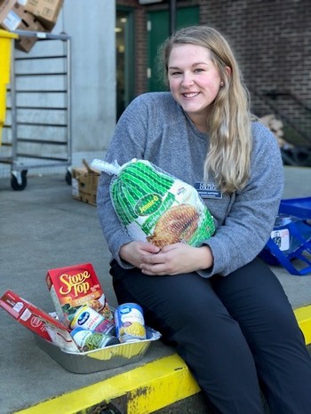 Student holding thanksgiving meal purchased from Duck Draw Fundraiser