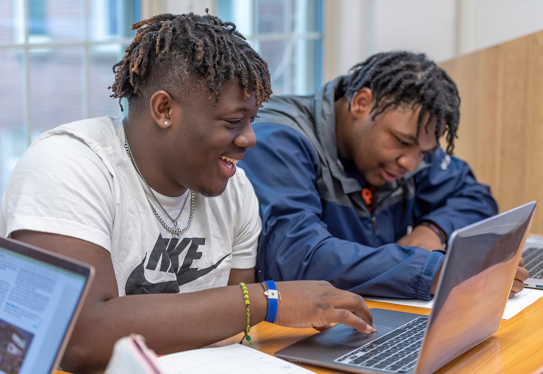 Two students in class working on laptop