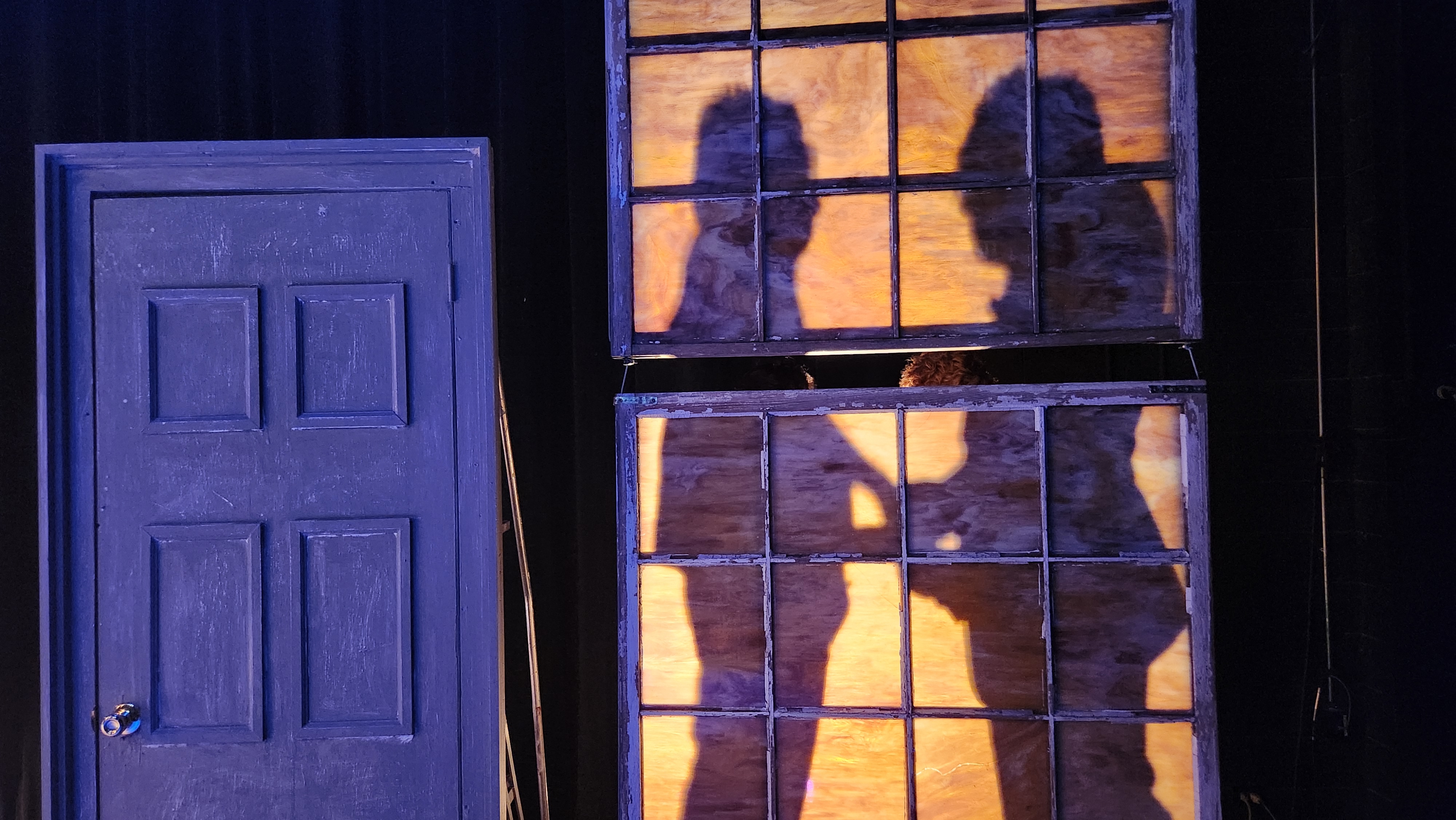 Set scene showing two shadows through a window from Songs for a New World