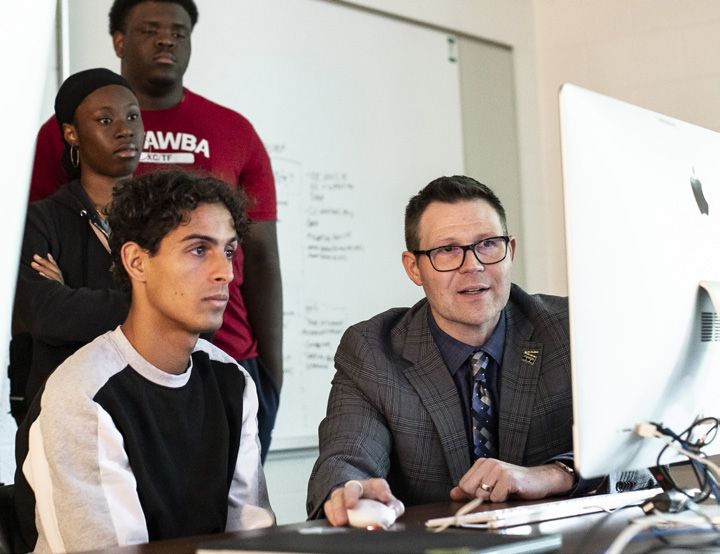 Students with faculty working on a computer